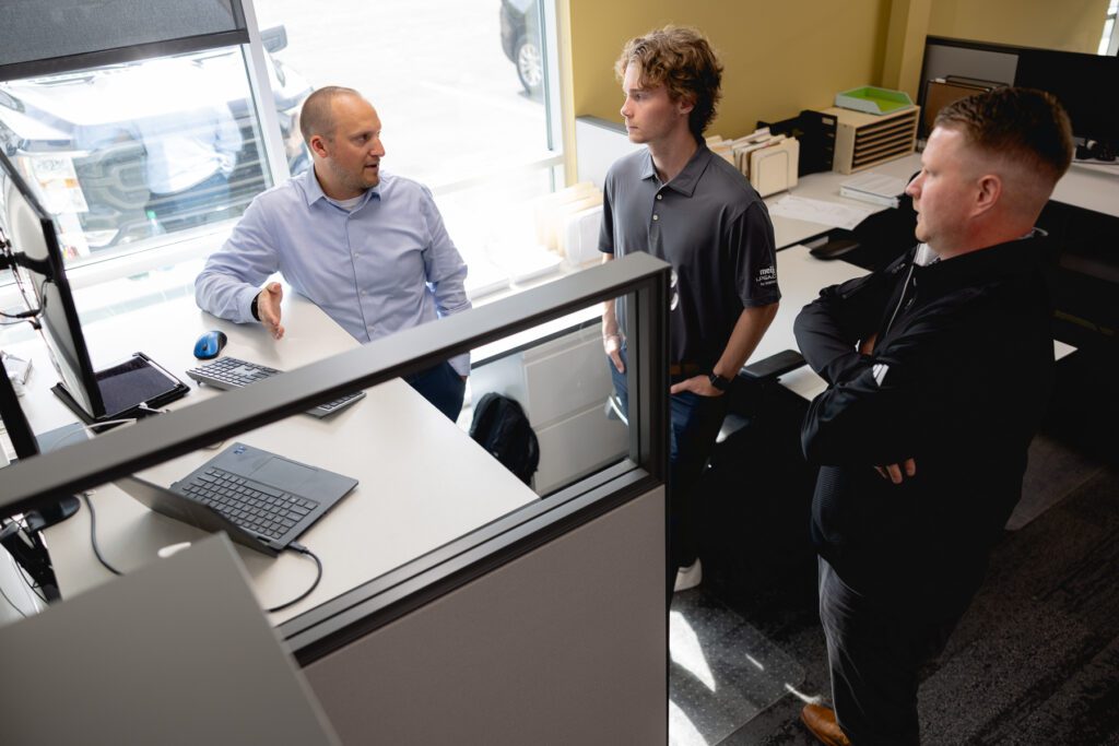 3 Veneklasen team members have a pre construction conversation while standing around a desk.