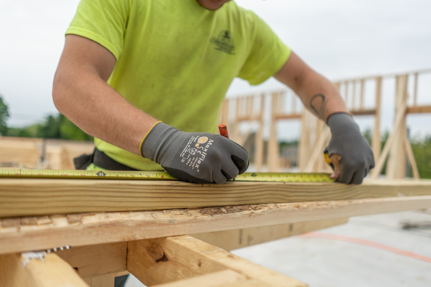 A member of the carpentry team, a subset of the general contracting team, measures on a job site.